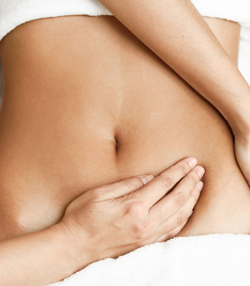 Top view of hands massaging female abdomen.Therapist applying pressure on belly. Woman receiving massage at spa salon